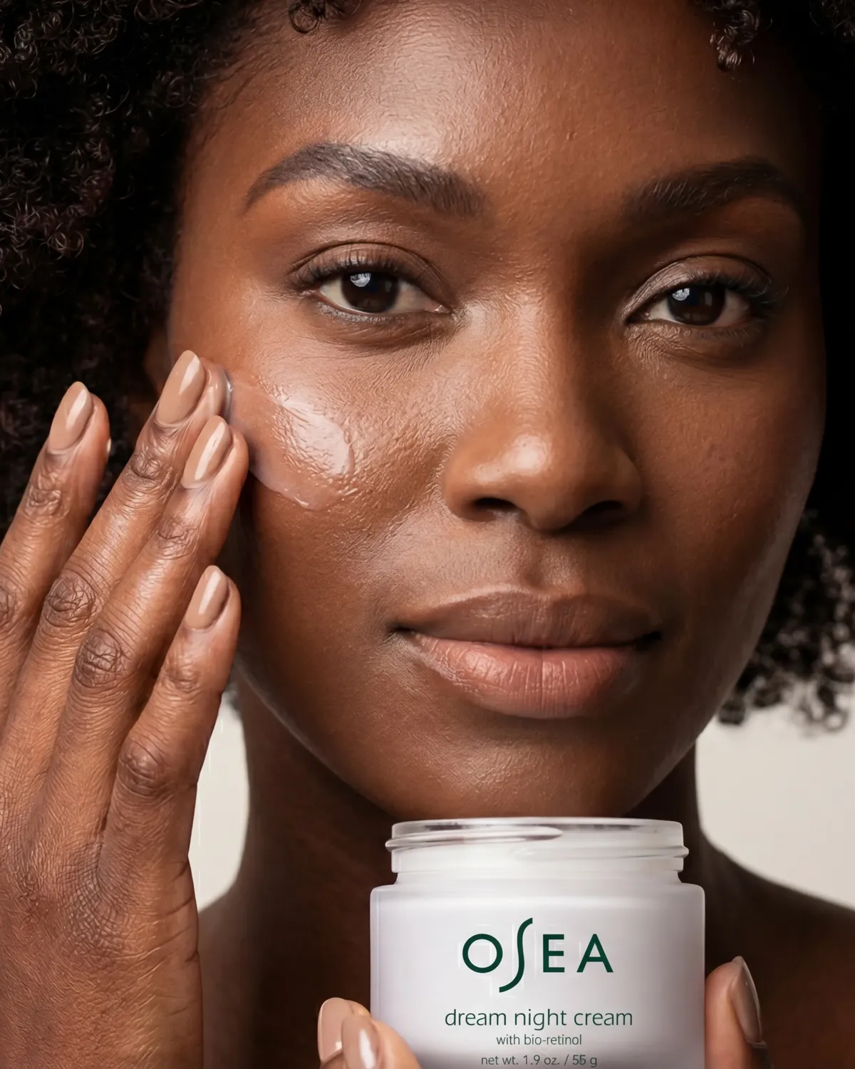Woman applying OSEA skincare cream with jar visible — AI beauty product photography for ecommerce brands